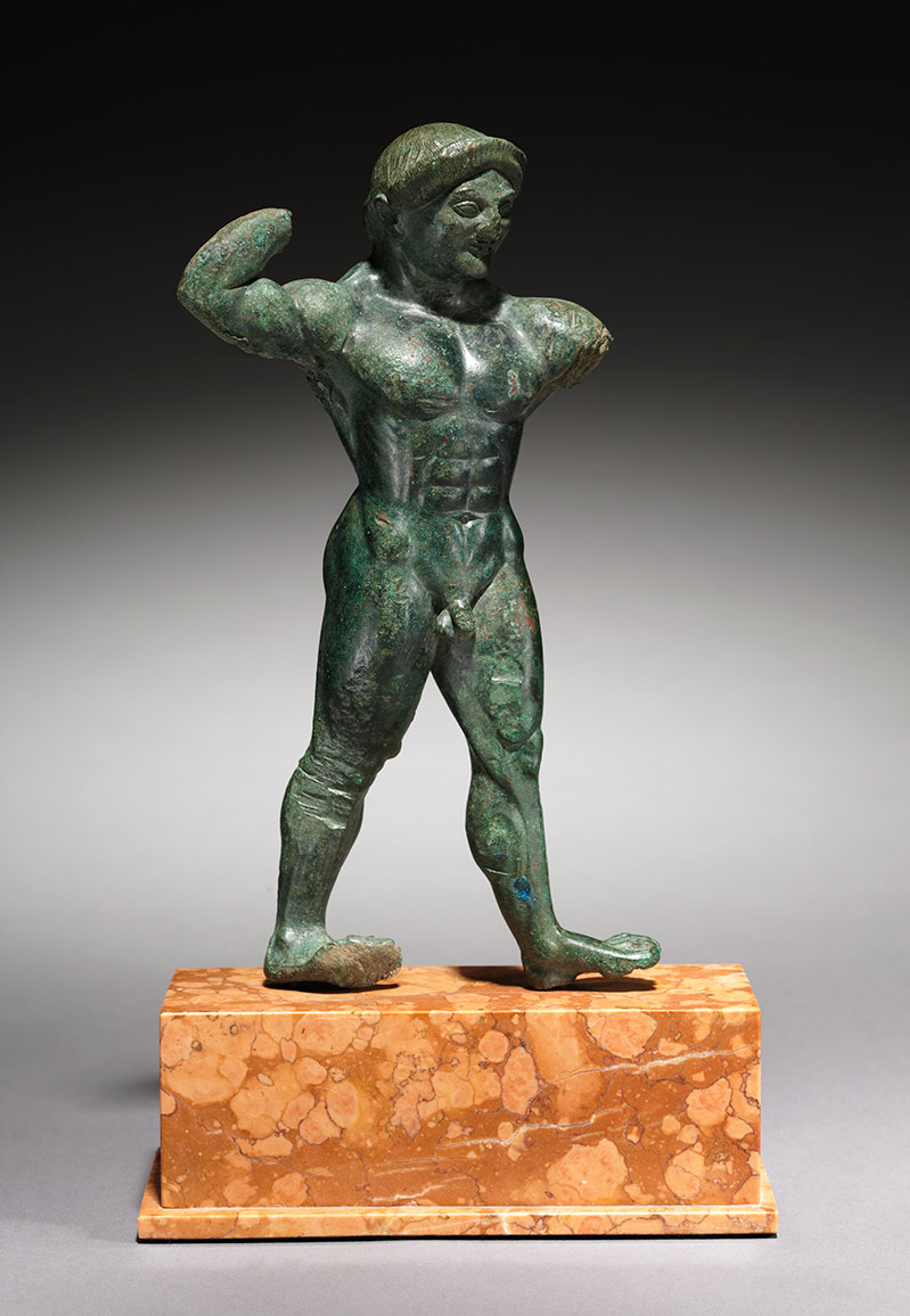 Bronze sculpture of a muscular male figure on a marble base, with arms raised and missing forearms, set against a grey background.